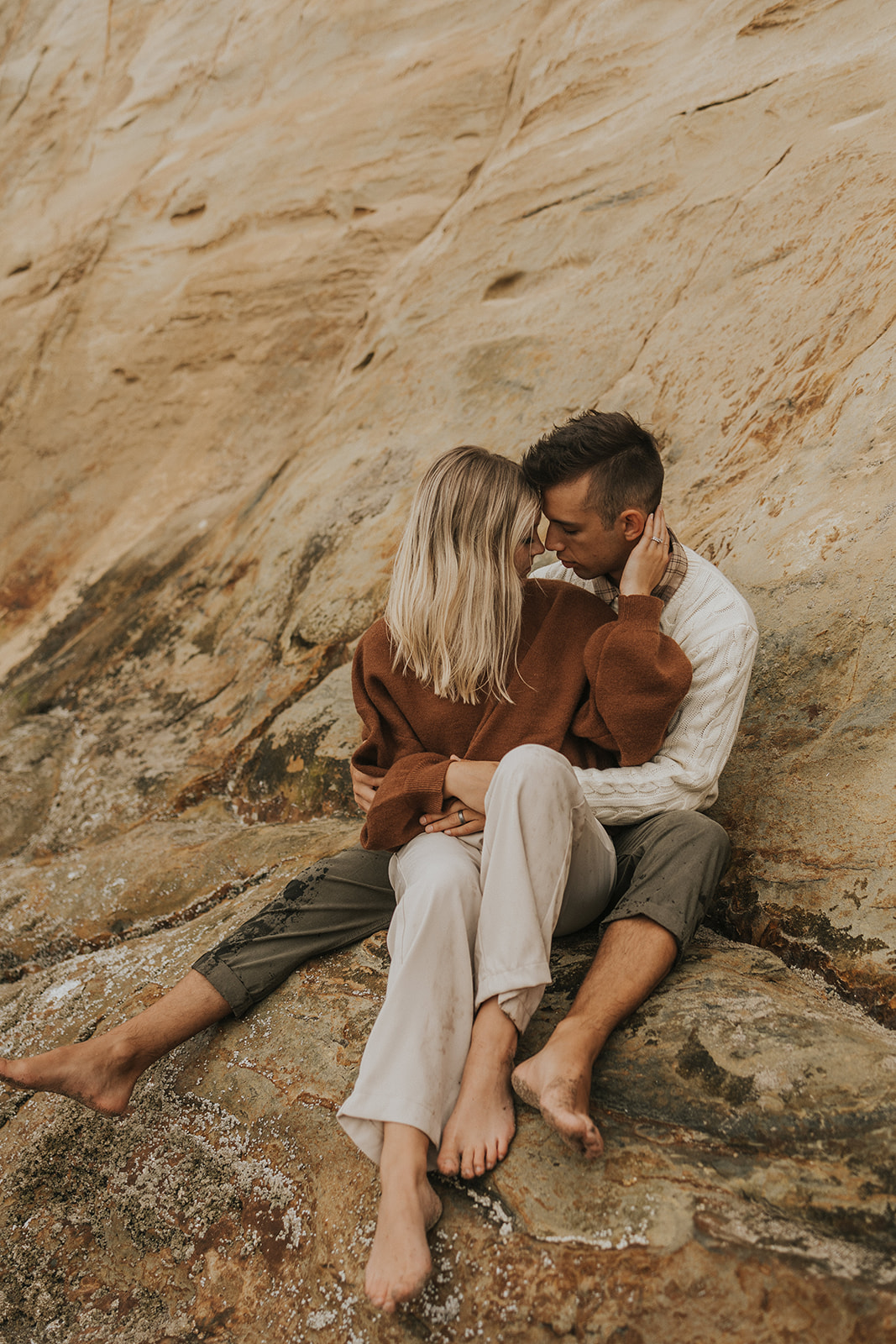 couple sitting on the rocks and kissing in oregon