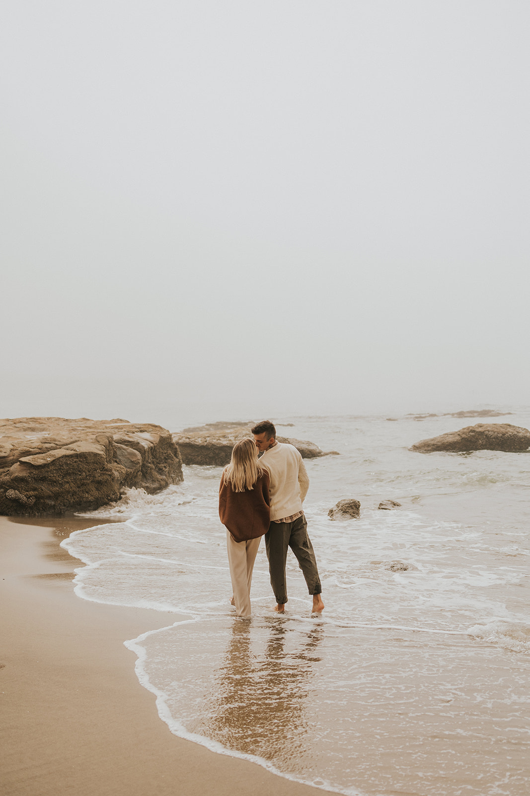 couple standing in the water on the beach in oregon