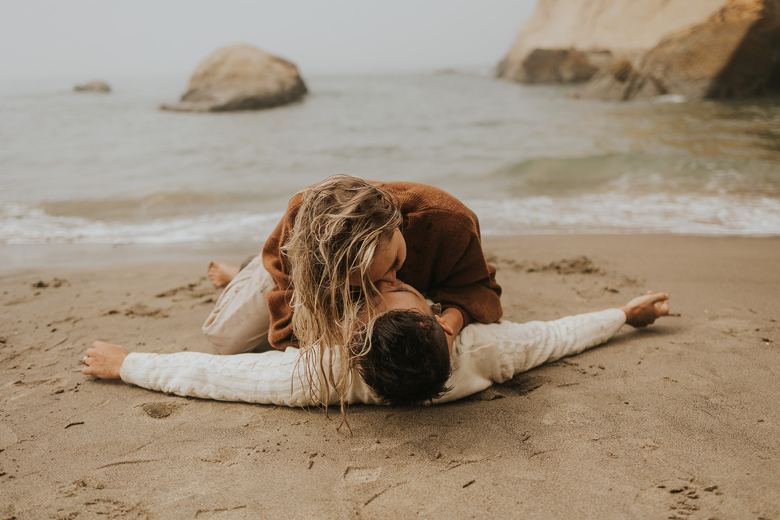 couple laying on the beach and kissing in oregon