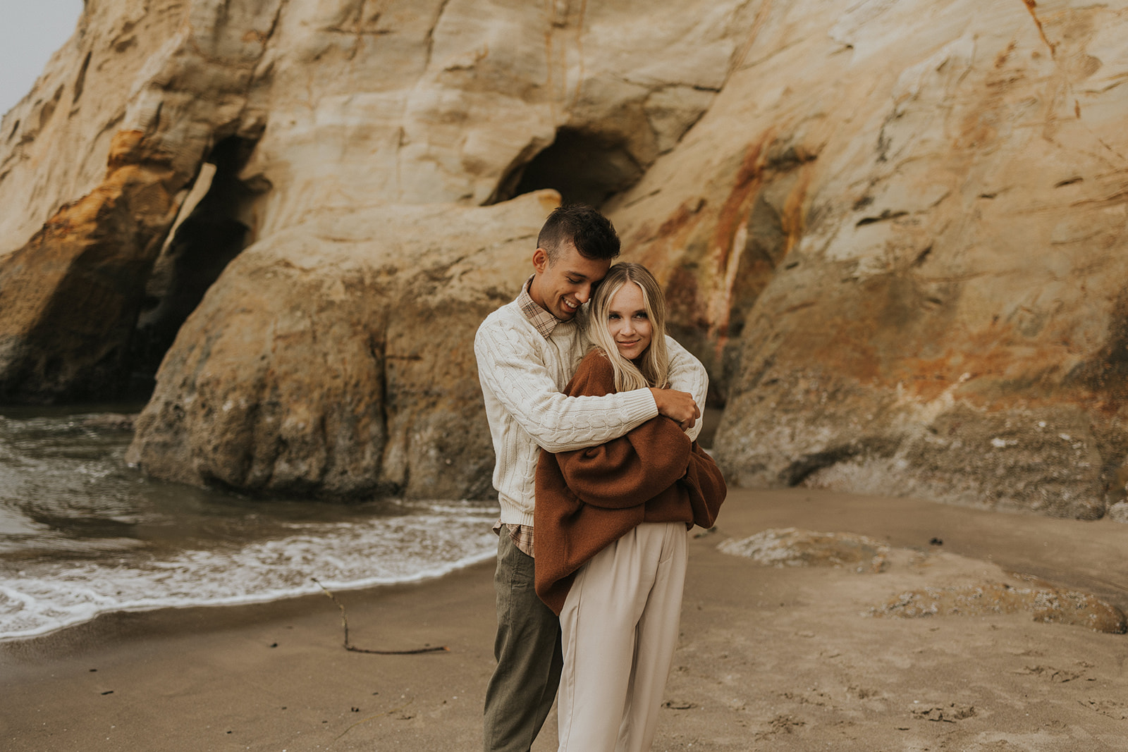 couple hugging on a beach in oregon