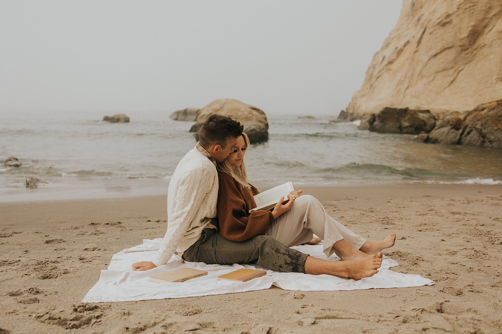 couple sitting on a towel on a beach in oregon