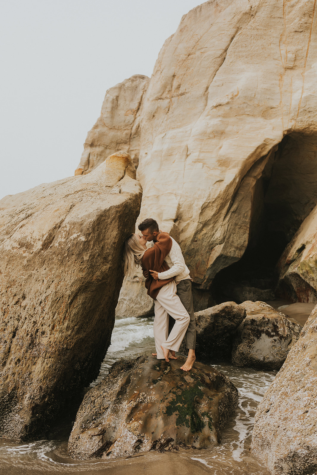 couple kissing on the rocks on the oregon coast