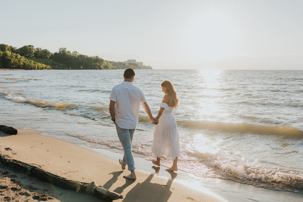 Couple walking alone the beach shore during engagement photoshoot beach session