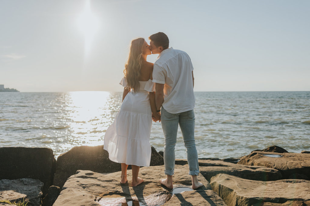 Couple kissing on beach rocks during engagement photoshoot beach session
