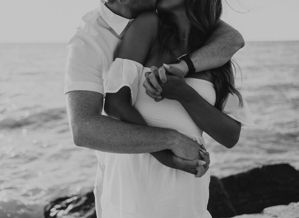 Man and woman holding eachother during beach engagement session