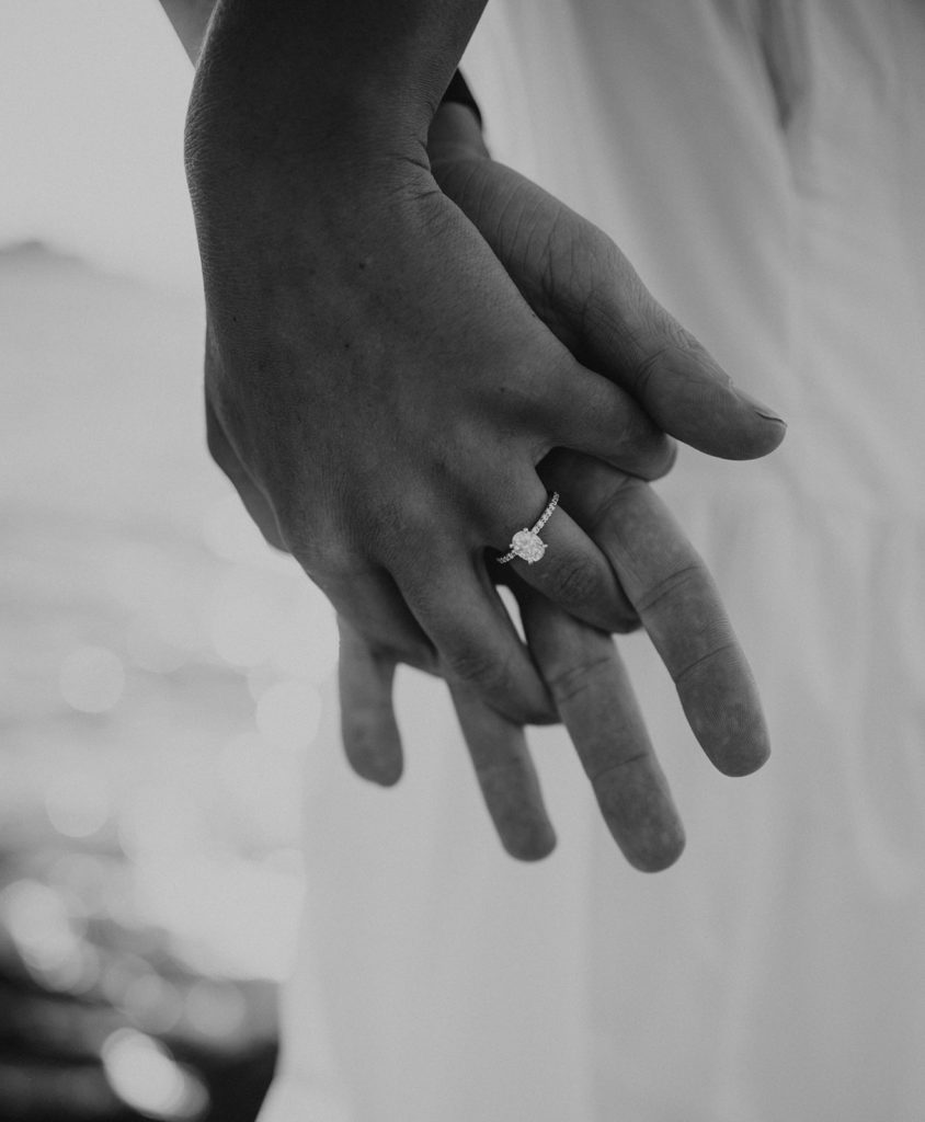 Newly engaged couple holding hands and showing engagement ring