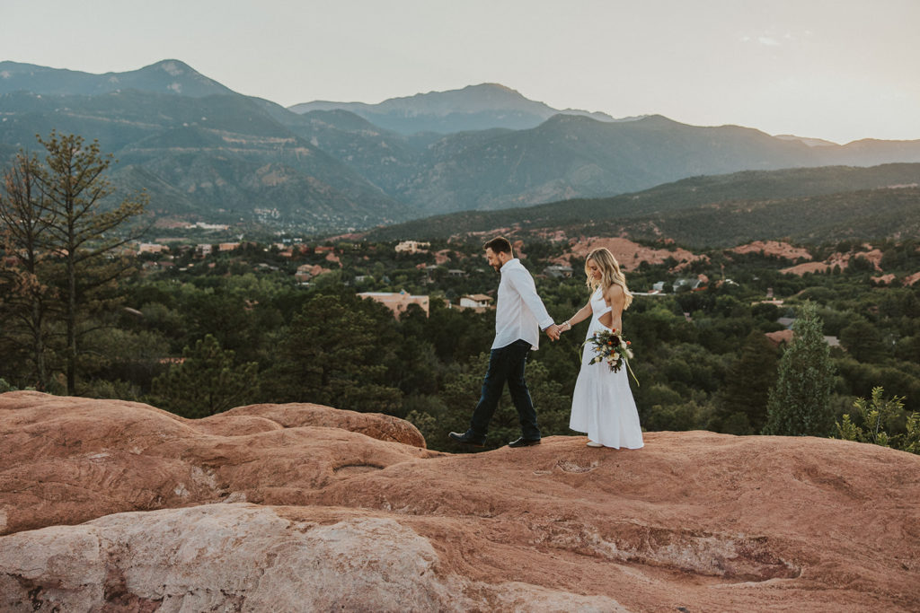 Bride and groom walking along mountains rocks for elopement photos