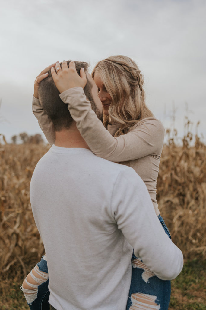 Newly engaged couple kissing for fall field engagement photos