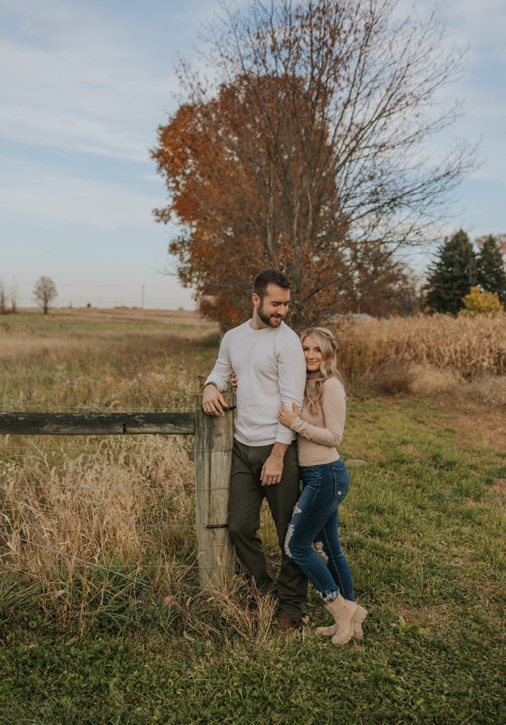 Newly engaged couple posing for fall field engagement photoshoot