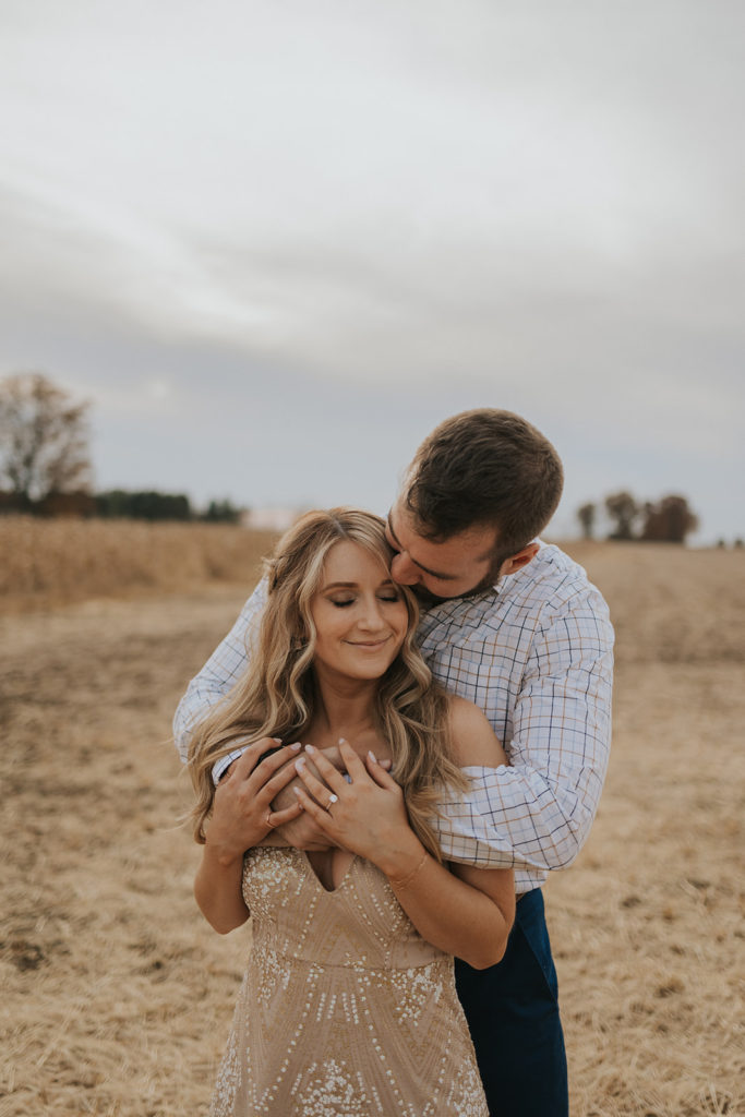 Man kissing fiance during fall engagement photoshoot