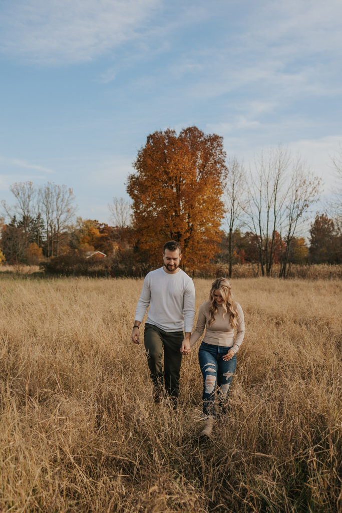 Newly engaged couple walking in ohio fields for engagement photoshoot