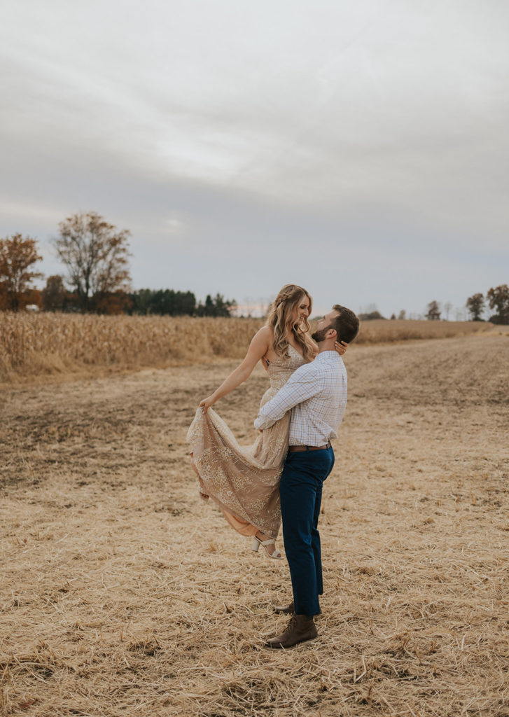 Man holding woman during fall field engagement photoshoot