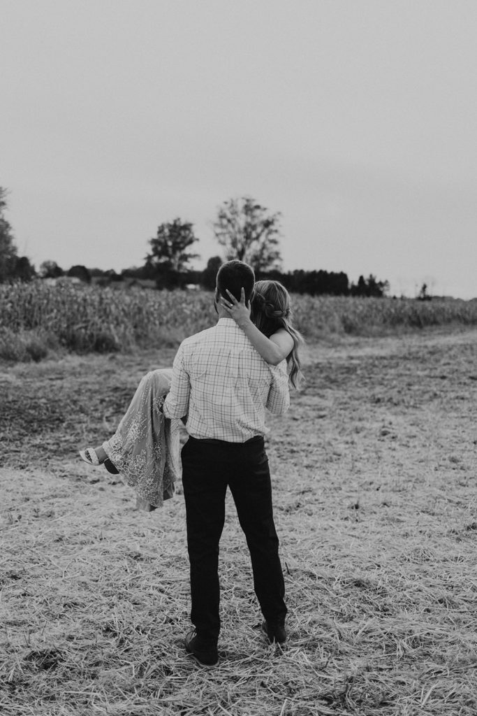 Man holding woman in black and white photo for fall field engagement photos