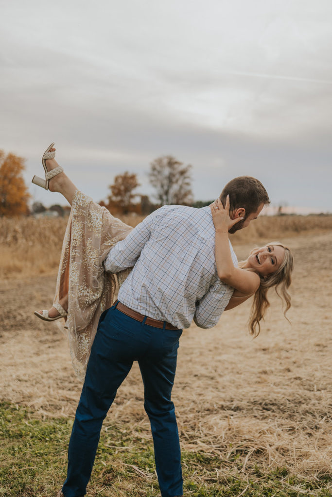 Man holding woman during fall engagement photoshoot
