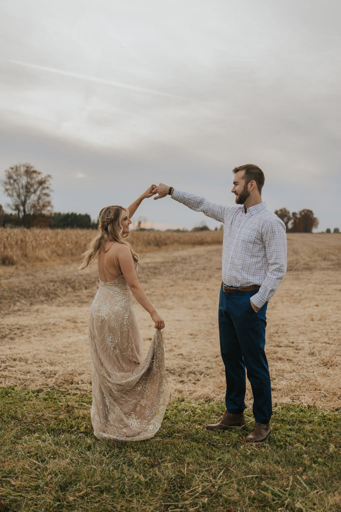 Man twirling woman around in a Ohio field for engagement photos