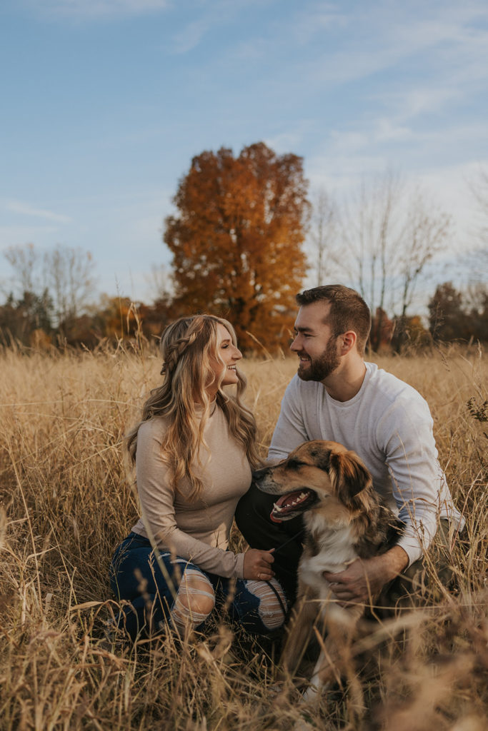 Newly engaged couple posing for engagement photoshoot with a dog