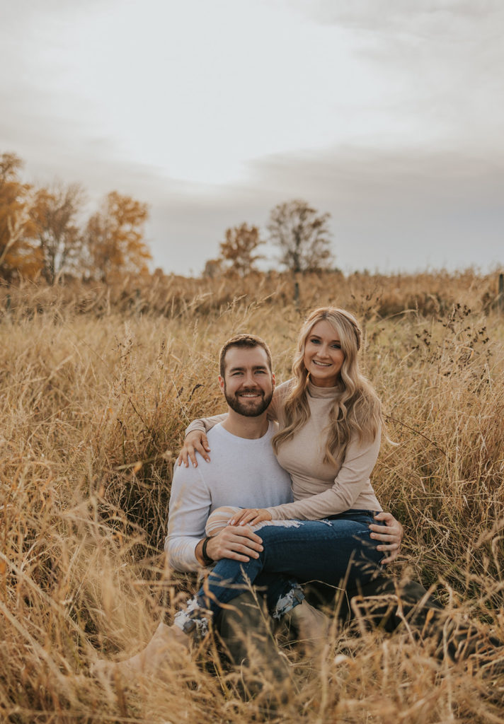Newly engaged couple sitting in a Ohio field for fall engagement session