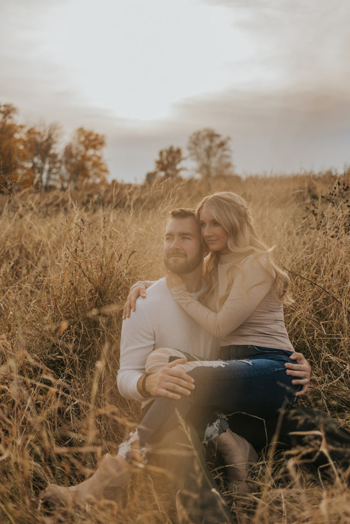 Newly engaged couple sitting in Ohio field for photoshoot