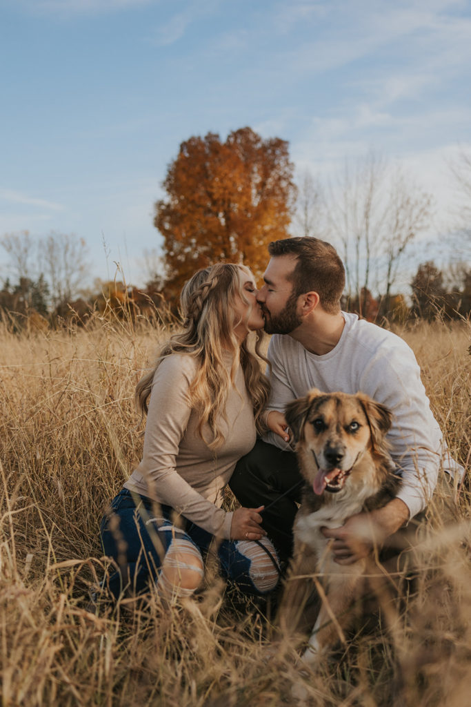 Newly engaged couple posing for fall engagement photoshoot with dog
