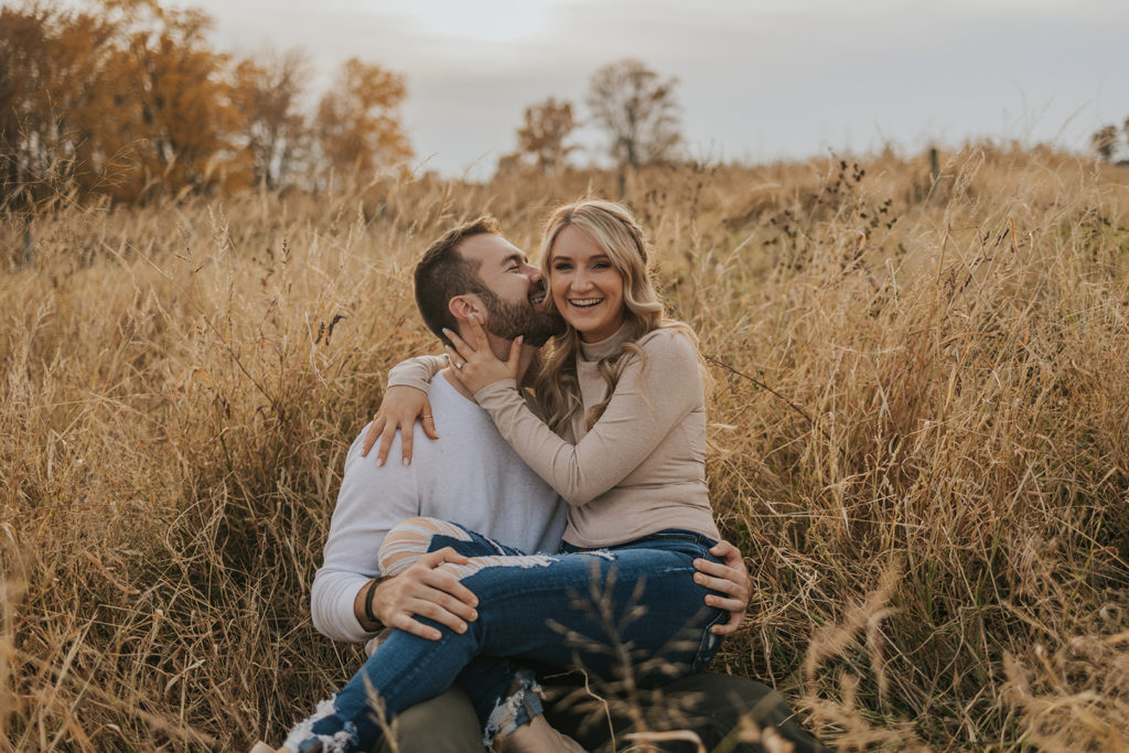 Newly engaged couple sitting in ohio fall field for photoshoot