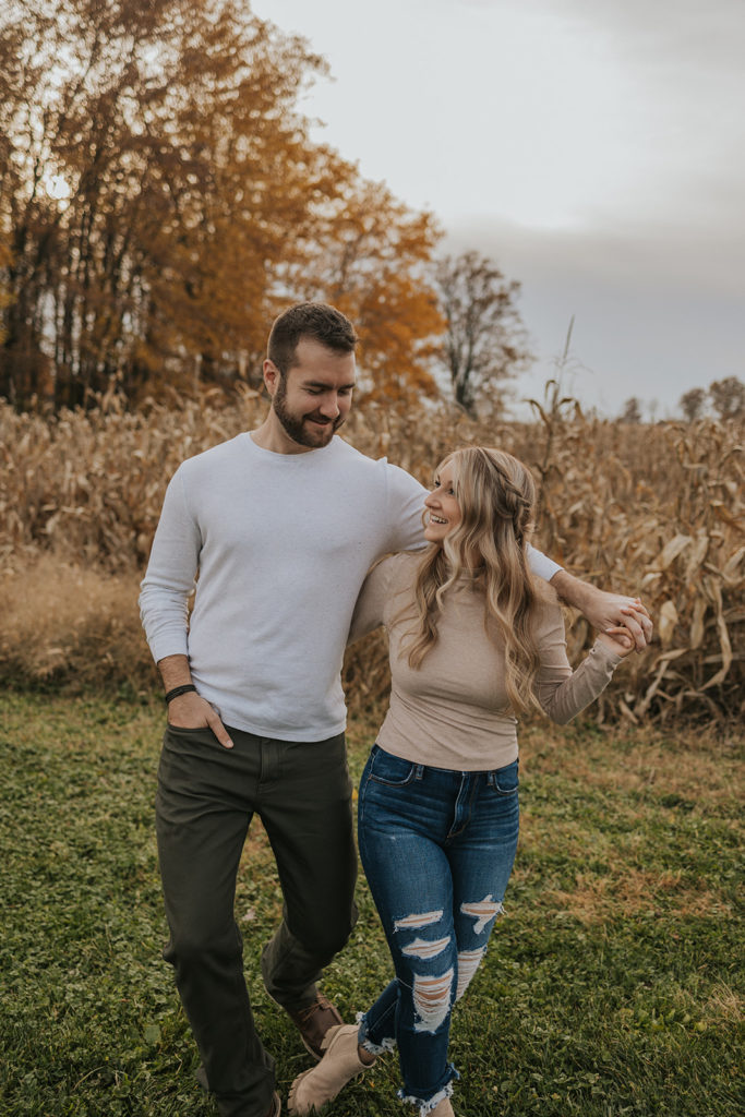 Playful couple posing for engagement photos in Ohio cornfield