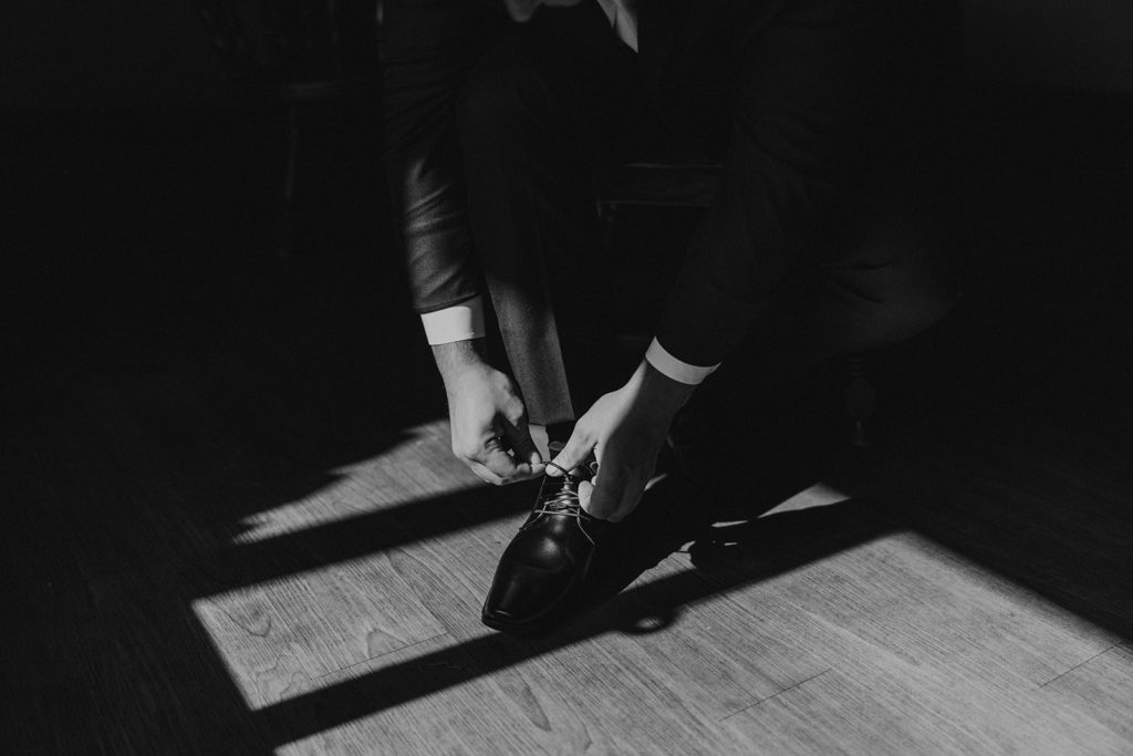 Groom tying his wedding shoes