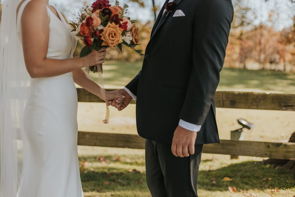 Bride and groom holding hands with wedding bouquet 