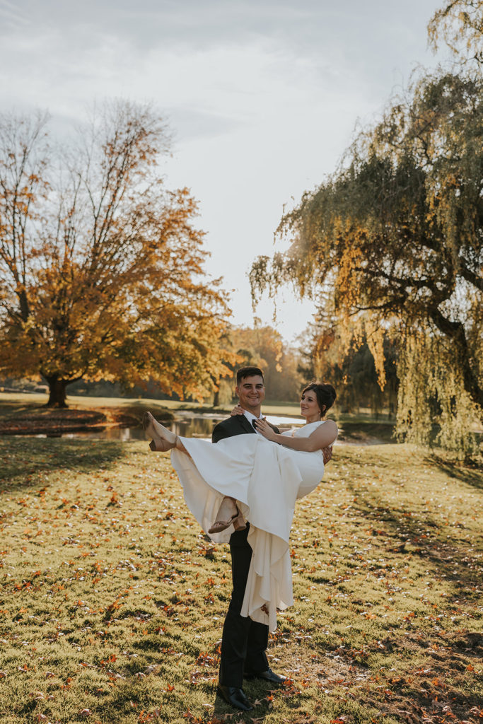 Groom holding bride in both arms for portraits