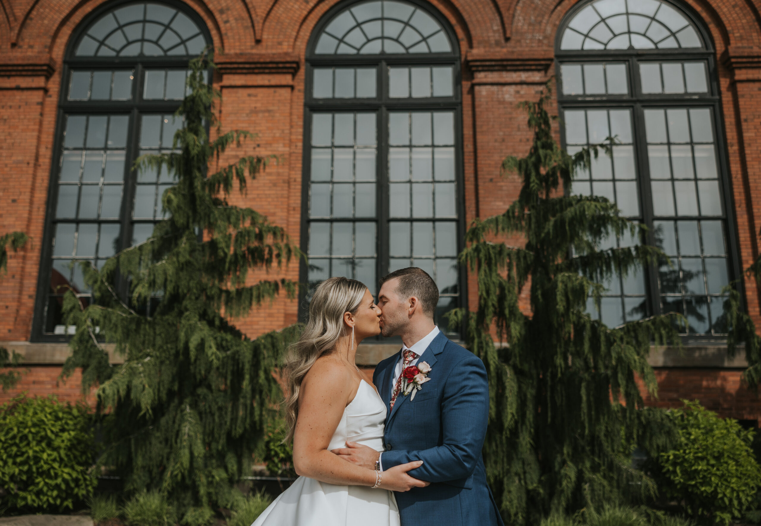Bride and Groom kissing in front of a brick building